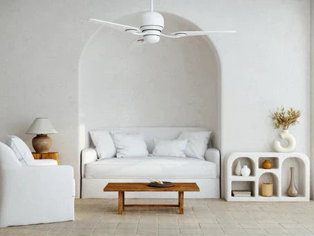 A modern minimalist white interior room with white ceiling fan and couch in alcove. The walls are painted with white limewash paint.