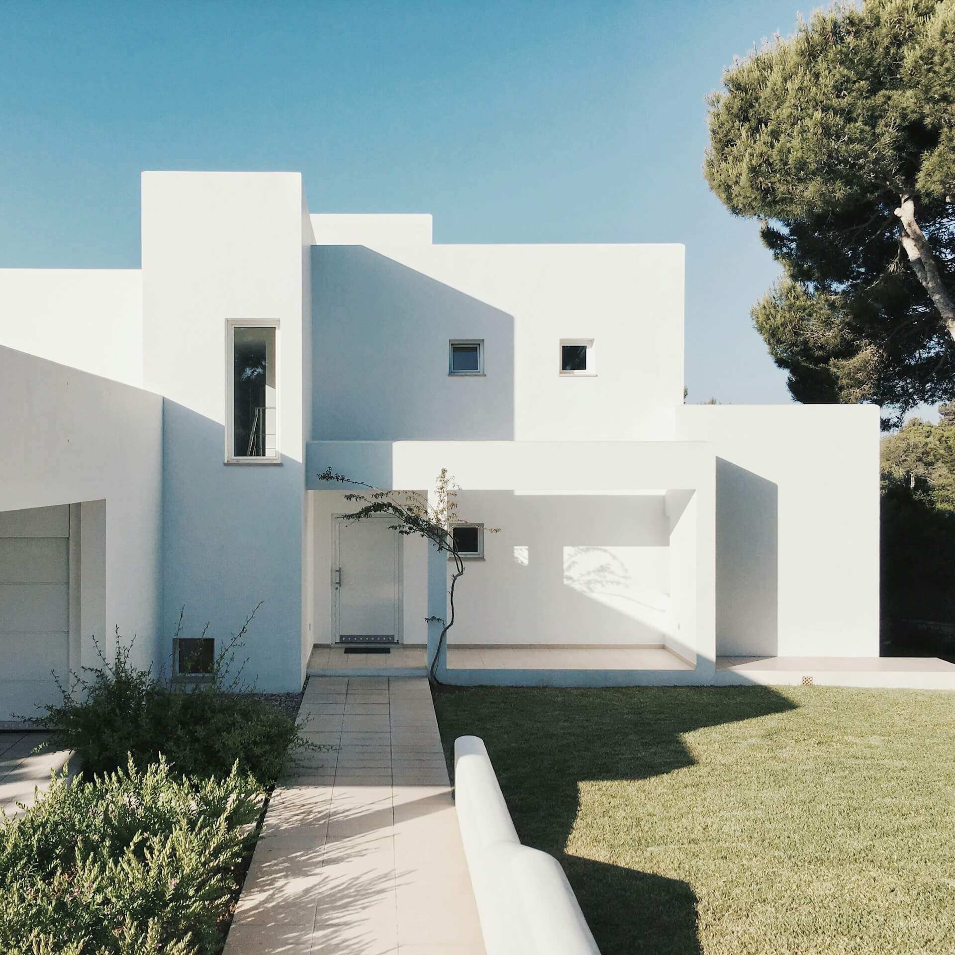 Large white house with brutalist architecture and white limewash exterior paint