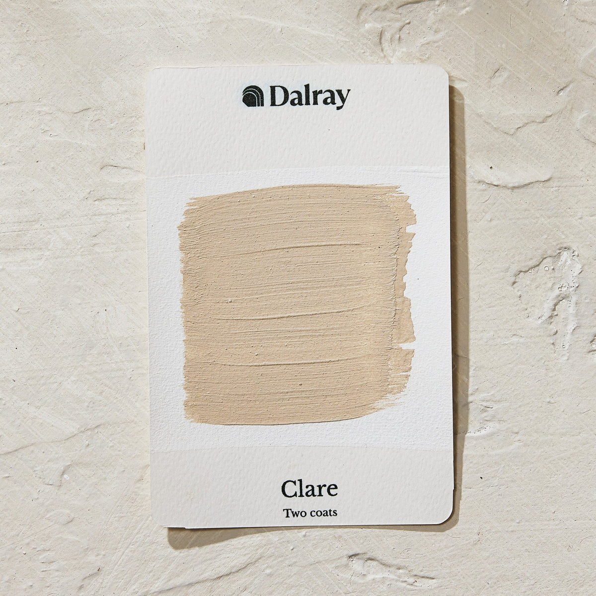 A Dalray paint swatch card labeled 'Clare Two coats' showing an earthy beige painted limewash swatch on a textured off-white background.