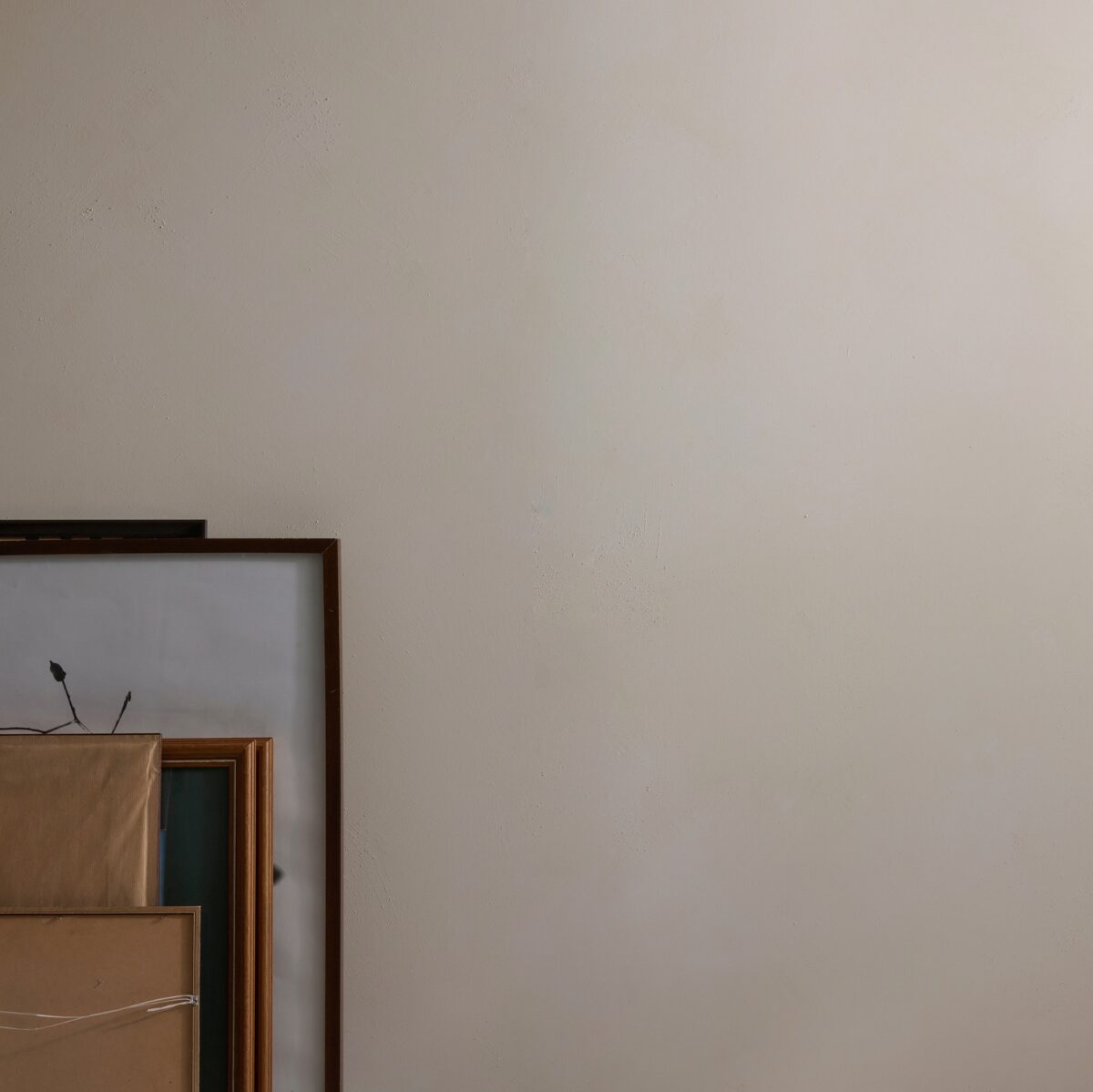 An off-white Chai Dalray Limewash wall with the corner of a framed artwork or print and stacked brown paper boxes visible in the lower-left corner.
