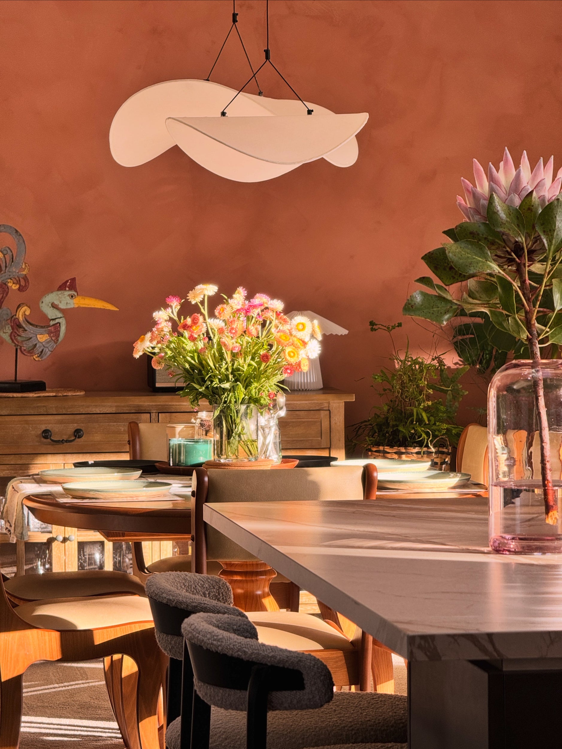 Dining area with tables, chairs, and decorative elements in a warm-toned room with australian limewash on back wall