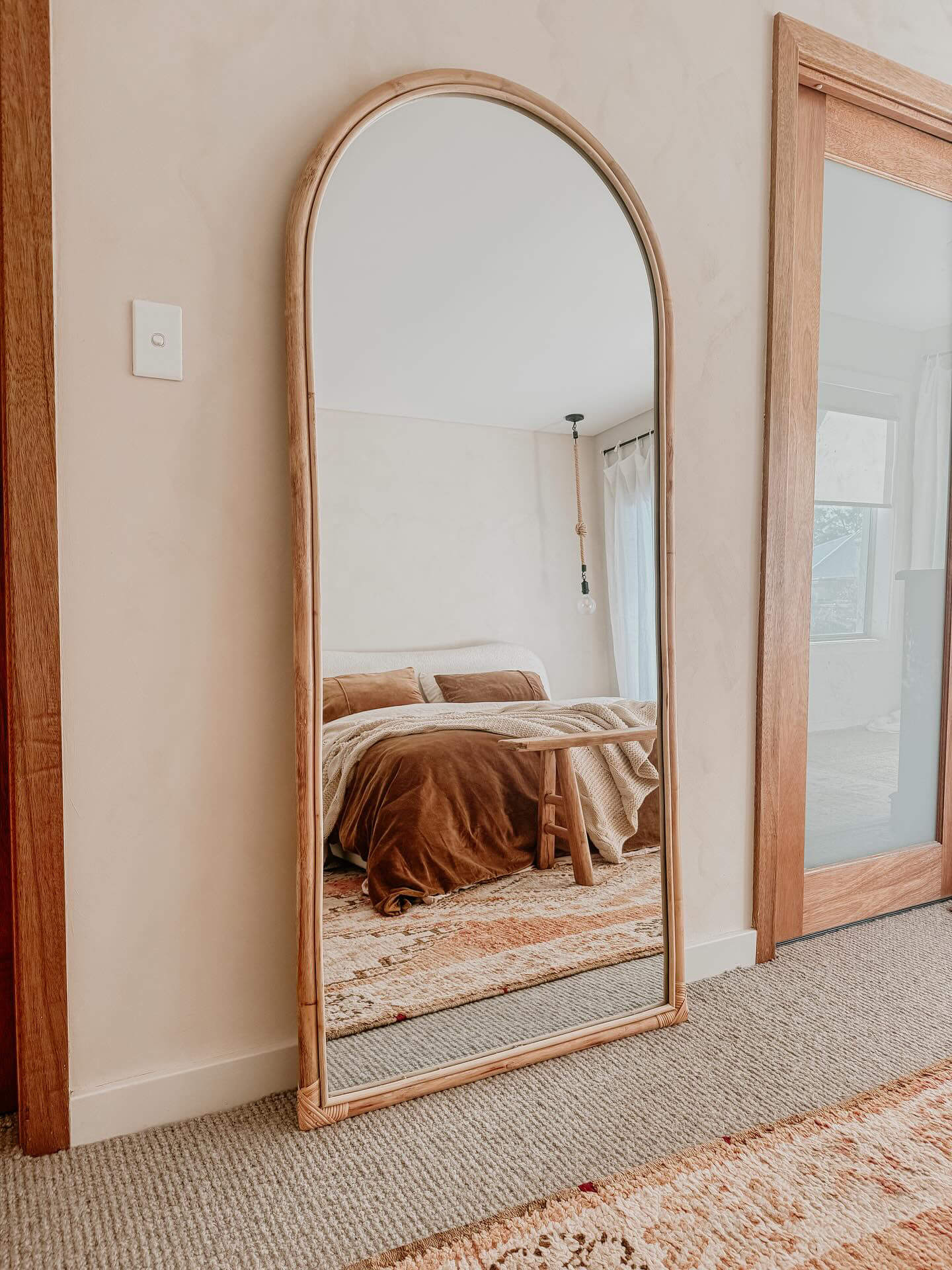 Wall with limewash paint and mirror, soft throws and wood trim
