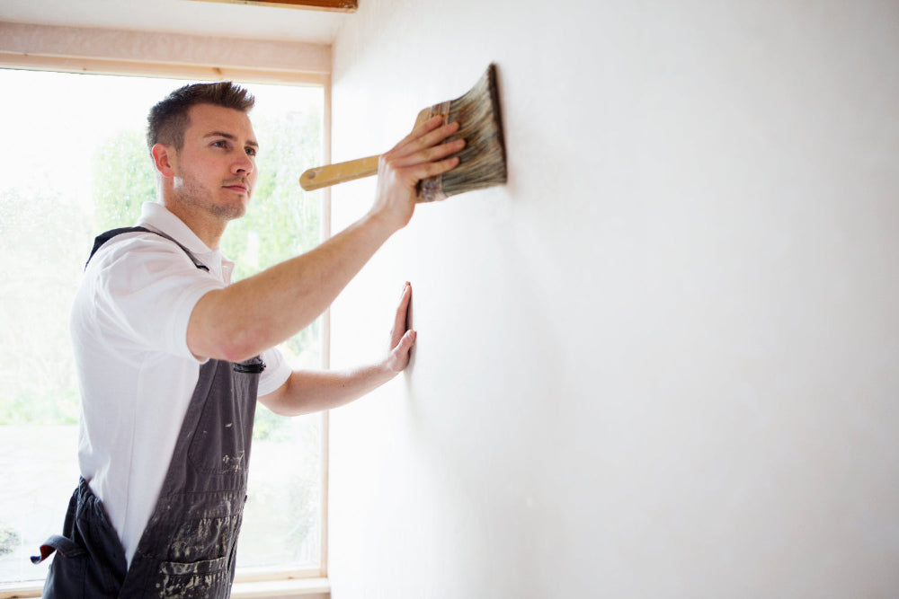 Man applying paint to a wall with a brush