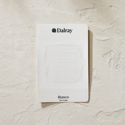 A Dalray Bianco Two Coat paint color card showing a textured white paint swatch, placed on a textured off-white plaster background.