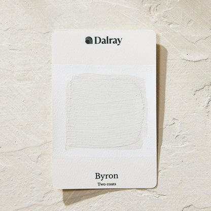 A Dalray paint colour card labeled 'Byron Two coats' showing a light warm gray textured limewash paint swatch, placed on a textured off-white surface.