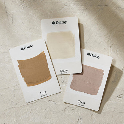Three Dalray warm limewash swatch cards labeled Lyre, Cream, and Terra, arranged on a textured off-white surface with soft shadows.