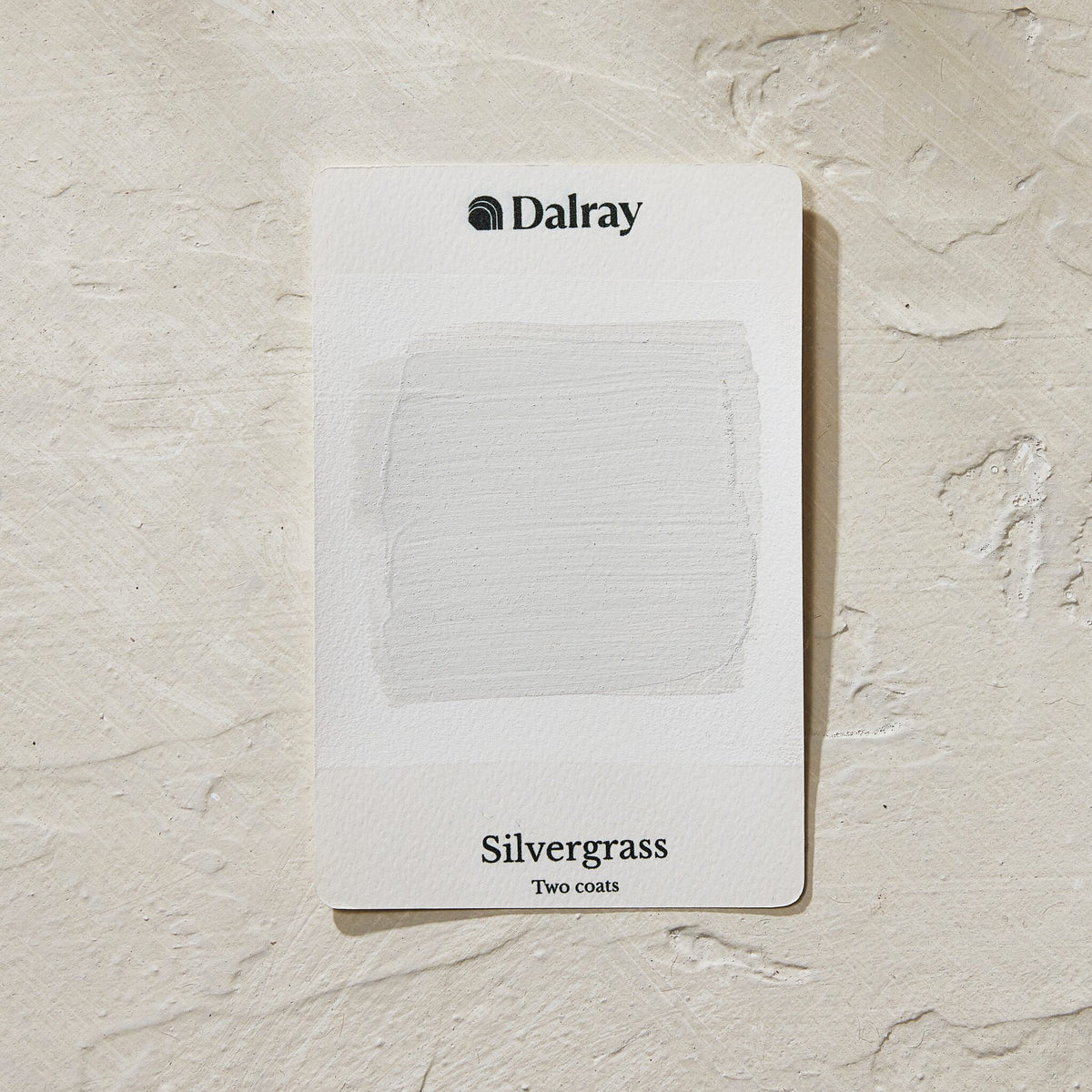 A Dalray paint swatch card labeled 'Silvergrass', a light greige with green undertones, with two coats applied, placed on a textured off-white surface.