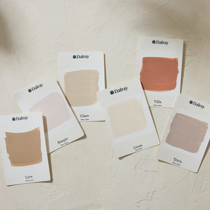 Six Dalray warm colour A6 limewash swatch cards arranged on a textured cream surface, showing different neutral shades including Lyre, Brique, Clare, Cream, Villa, and Terra.
