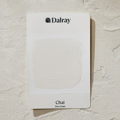A Dalray paint swatch card labeled 'Chai Two Coats' showing a textured off-white limewash paint swatch, placed on a matching textured off-white surface.