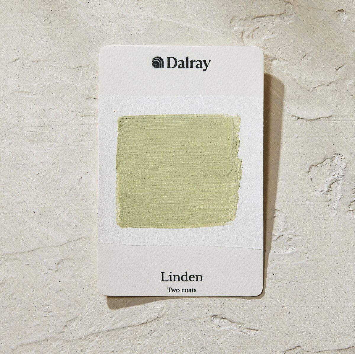 A Dalray paint color card showing the color 'Linden' with two coats applied, in a light sage green shade, displayed on a textured off-white plaster background.